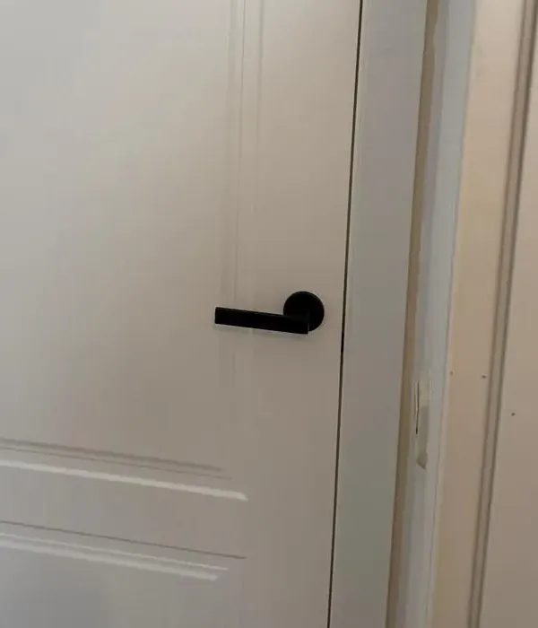 Detalle de manilla negra sobre puerta lacada en blanco